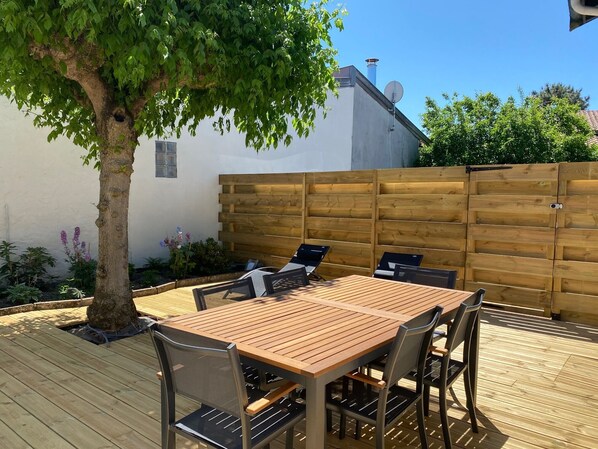 Terrasse équipée d’une table 6 chaises 2 bains de soleil 2 chiliennes 1 barbecue