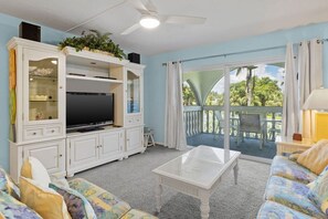 Entertainment console with flat screen TV and adjoining patio overlooking gorgeous lush grounds and pool