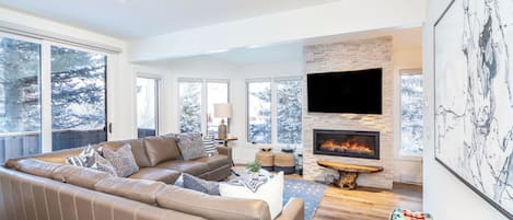 Bright and spacious living room with a large sectional, TV, and fireplace.