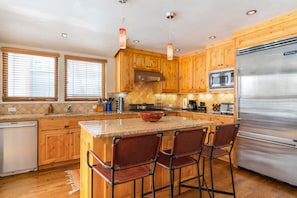 Spacious kitchen with an oversized fridge, modern appliances, and barstool seating at the large island.