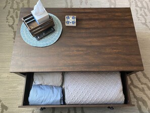 Open drawer of coffee table to find sheets/blankets 
