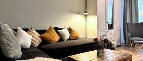 Wohnzimmer mit ausziehbarer Eckcouch. Kissen, Decken, TV.