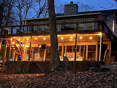 Back deck of house. Whiskey barrel bar area with TV and large porch swing bed.