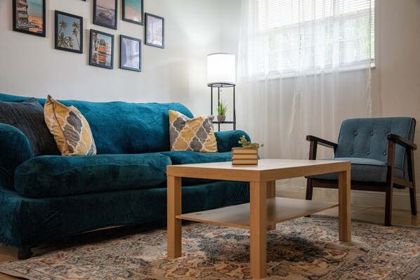 Charming living room with a comfortable blue sofa, perfect for unwinding while watching your favorite shows on the smart TV. A stylish blend of vintage decor and modern comfort.