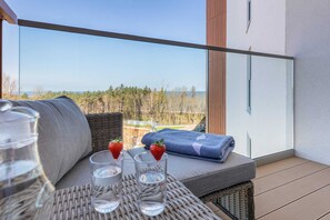 A modern balcony with rattan-style furniture, including a coffee table and seating with cushions, perfect for relaxing outdoors.