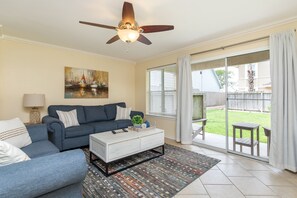 Open concept living area with modern furnishings and bright light shinning in from the patio space