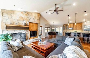 The gorgeous open-concept living/kitchen/dining area features comfortable and stylish furnishings, rustic touches and a striking stone fireplace that make for a lovely gathering space for your family and friends.