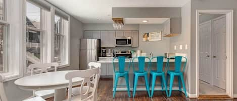 The dining and kitchen areas in this bright and beautiful home, boasting seating for eight between the bar and dining table.