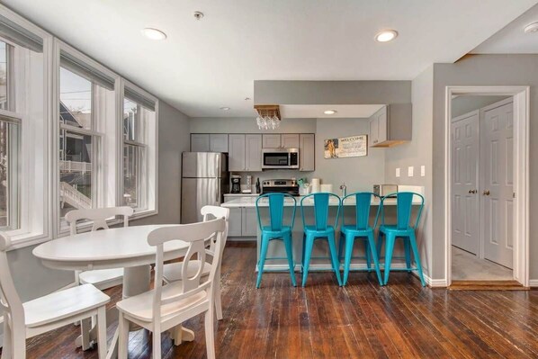 The dining and kitchen areas in this bright and beautiful home, boasting seating for eight between the bar and dining table.