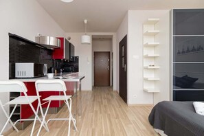 A modern kitchen with vibrant red cabinets, a dining table with white chairs, and wooden flooring.