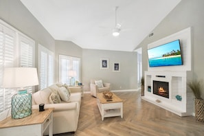 Living Room with Fireplace and Smart TV - Cozy up after a beach day with the electric fireplace, 55” smart TV, and plenty of seating. Just 7 minutes from the Pier and Coast Guard Station Beach, and even closer to island eats like Golden Isles Olive Oil and Iguanas.