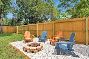 Private fenced in backyard with firepit and Adirondack chairs