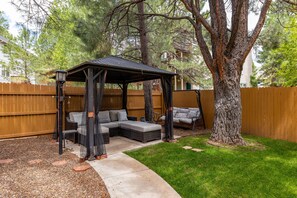 Fully fenced Yard with a new outdoor sectional tucked under the trees.