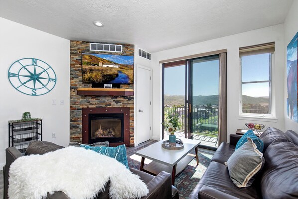 The Mason at Stillwater 3070: Cozy sofa set by the fireplace, overlooking the serene balcony view.