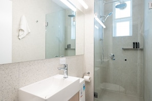 Modern bathroom with mirror cabinet for storage, soft towels, and rainwater showerhead.