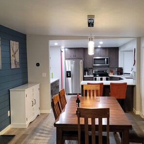 Dining table, server with wine and cocktail glasses, kitchen