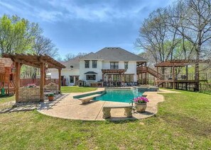 Enjoy this backyard oasis. A pool with a diving board, and deck with creek views