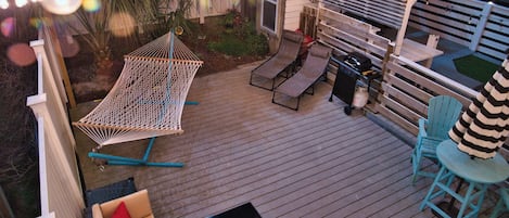 Back patio with gas grill, hammock, fire table, sun loungers, & night lighting
