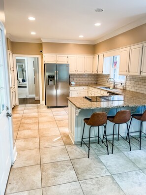 spacious kitchen with 4 barstools and table seating for 4.