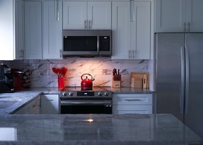 A stylish kitchen with sleek finishes and vibrant pops of red.