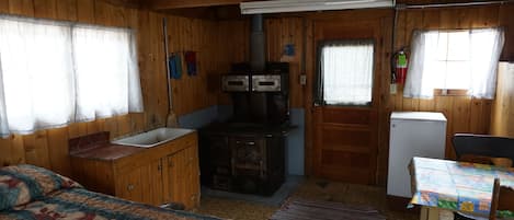 Cabin 10 is a cozy rustic cabin that features a wood-burning stove.