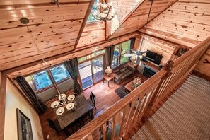 Take in the stunning view from our second-floor loft! Your perfect escape features a cozy living area, a charming dining area, and a balcony with a hot tub, outdoor dining area, and BBQ grill. Imagine yourself enjoying a meal with loved ones, relaxing in the hot tub, or simply savoring the breathtaking scenery.