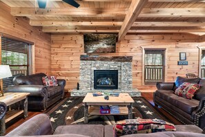 Living room has stone gas fireplace, lots of seating, love seat, and large flat-screen TV.