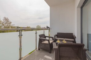 Balcony with glass railing, offering a peaceful outdoor spot with seating. The view overlooks the surrounding area, providing a serene space for relaxation.