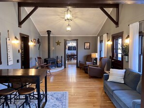 Main living room with a door to the side deck and a cozy wood stove.