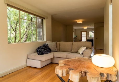 Unwind on the plush sectional surrounded by leafy outlooks—ideal for slow mornings, quiet reading, or evening chats.