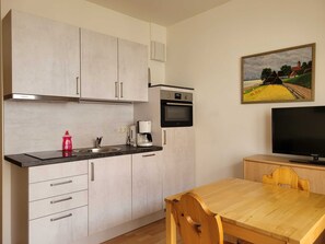 Wohnküche mit Esstisch und Couch sowie Zugang zum Balkon