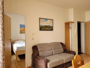 Wohnküche mit Esstisch und Couch sowie Zugang zum Balkon