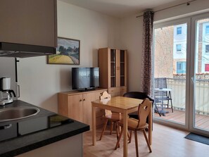 Wohnküche mit Esstisch und Couch sowie Zugang zum Balkon