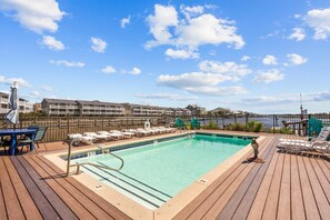 Pool with lounge space and outdoor shower overlooking canal. 