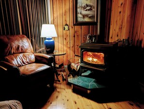 Wood burning fireplace next to leather sofa at night in living room