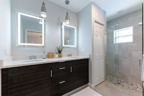 The Master bathroom sits just off the Master bedroom with a double white & dark wood vanity, double LED lit mirrors and step in rain shower.