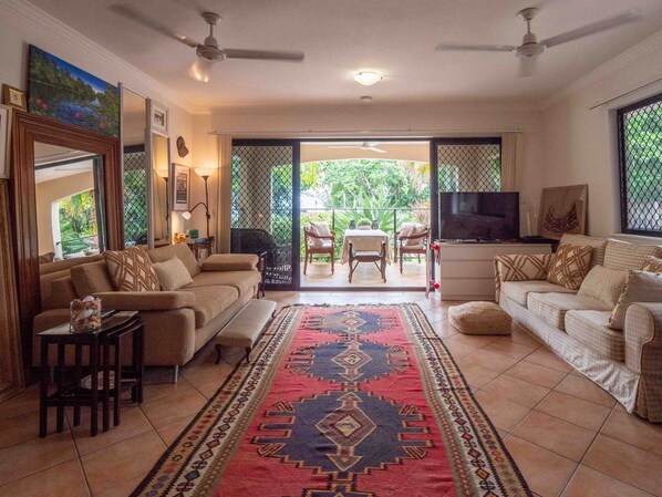 Beautiful, spacious living room and front deck, surrounded by tropical greenery