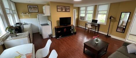 Living Room, looking over hand-painted table to kitchen, TV with 
Rokku, desk.
