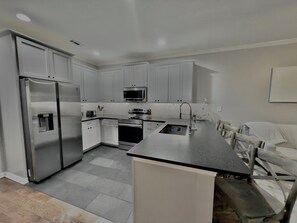 Stainless appliances and large dark granite countertops in renovated (2024) kitc