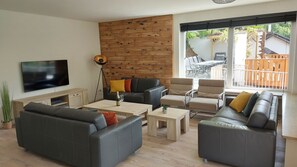 Wohnzimmer mit Smart-TV und Zugang zum Balkon und Küchen.