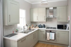 Modern kitchen with fridge, freezer dishwasher, gas hob, oven & microwave.