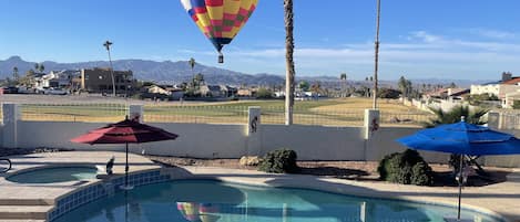Private pool with palm trees, a golf course view and a balloon making a flyby.