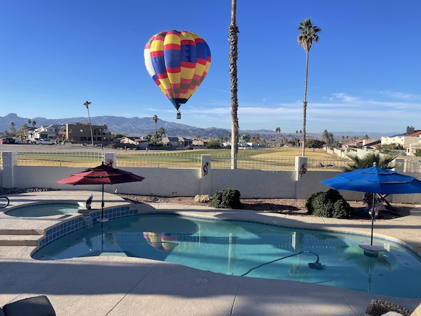 Private pool with palm trees, a golf course view and a balloon making a flyby.