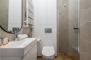 The bathroom's contemporary design includes fresh towels and a hairdryer.