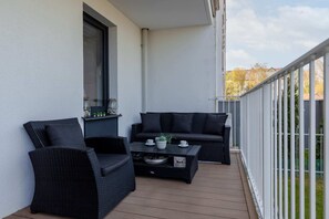 The balcony offers a serene outdoor space with a stunning view of the surrounding area. It is furnished with a small table and chairs, ideal for enjoying a morning coffee or relaxing in the evening.
