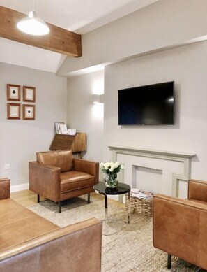 Modern lounge area with leather sofa, 2 matching chairs and Smart TV.