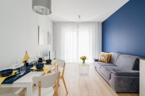 Modern living room with a sofa bed, TV and dining area.