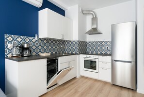 Kitchenette with induction hob, oven, fridge, freezer, electric kettle, coffee maker and dishwasher.
