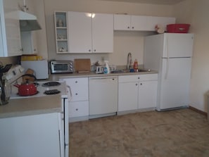 This kitchen has an electric stove, microwave, refrigerator,  and stock kitchen.