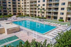 Sparkling outdoor pool surrounded by lush greenery and lounge chairs.